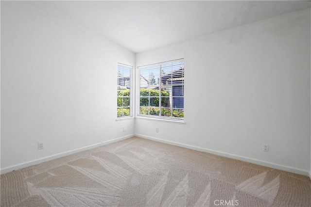 empty room with baseboards and light colored carpet