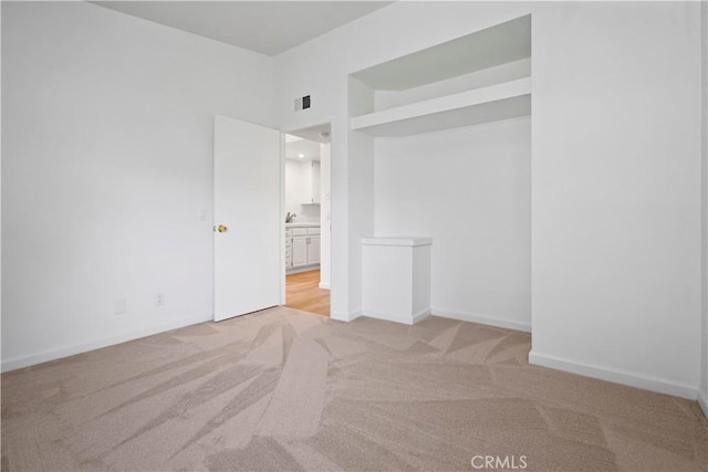 unfurnished bedroom with light carpet, ensuite bath, and baseboards