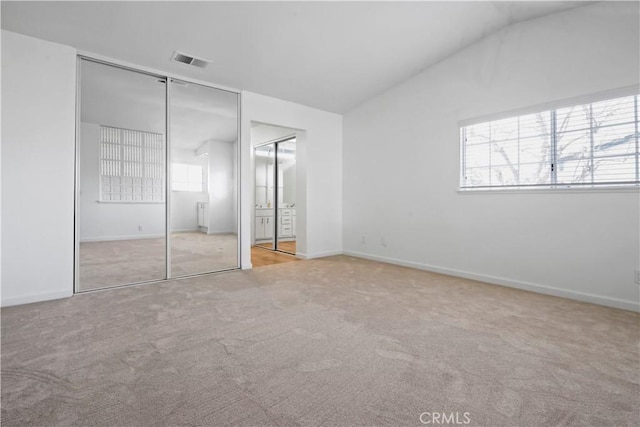 unfurnished bedroom with carpet, vaulted ceiling, ensuite bathroom, and baseboards