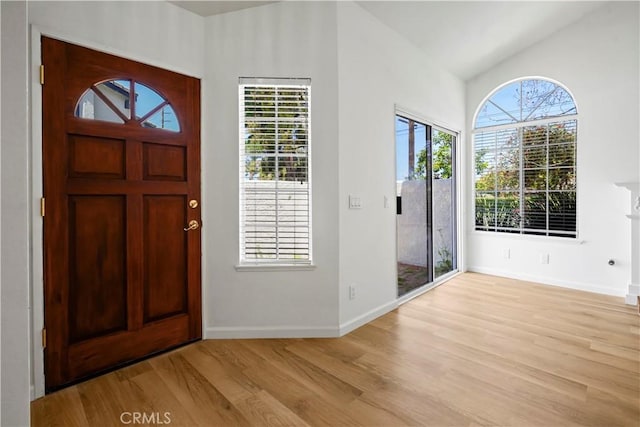 foyer featuring wood finished floors, vaulted ceiling, and baseboards