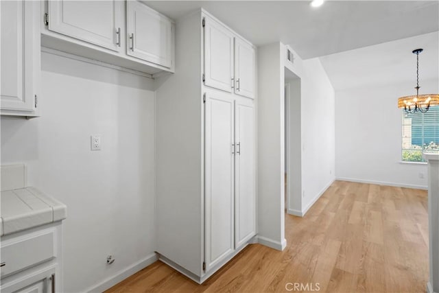 mudroom featuring a chandelier, baseboards, and light wood-style floors