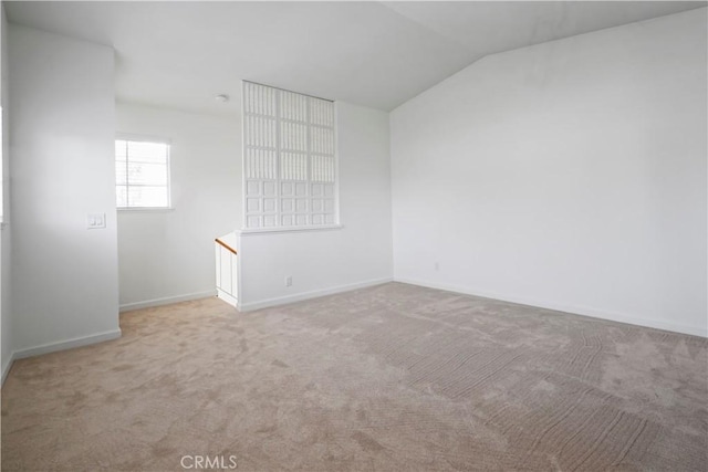 empty room with carpet, vaulted ceiling, and baseboards