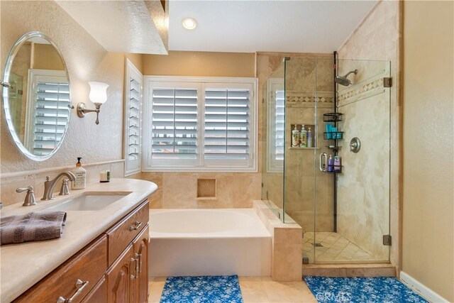 bathroom with a garden tub, tile patterned flooring, a stall shower, vanity, and a textured wall