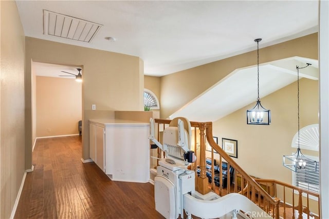 corridor featuring visible vents, an upstairs landing, wood finished floors, baseboards, and a chandelier