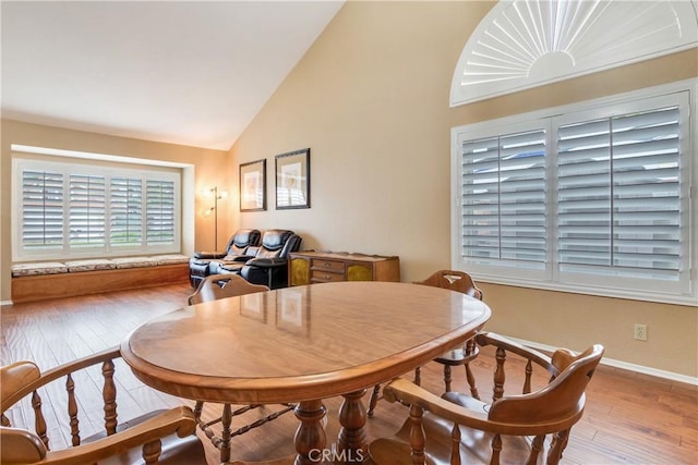 dining room featuring baseboards, high vaulted ceiling, and hardwood / wood-style floors