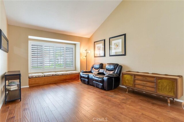 sitting room with baseboards, vaulted ceiling, and wood finished floors