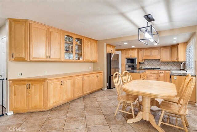 kitchen featuring decorative backsplash, light brown cabinets, glass insert cabinets, a sink, and stainless steel appliances