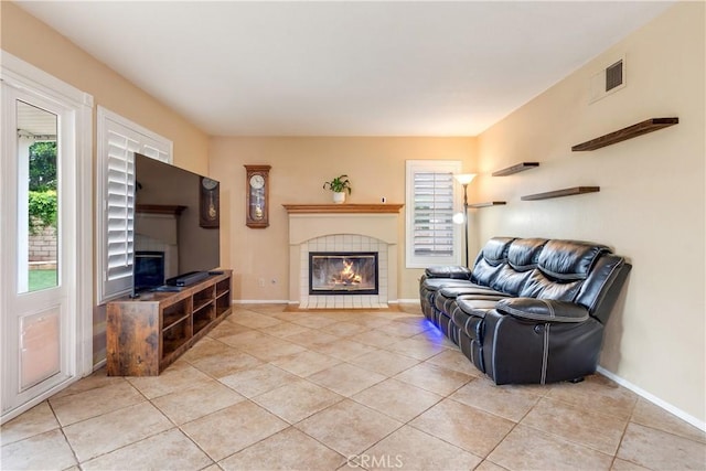 living room with baseboards, visible vents, light tile patterned floors, and a fireplace