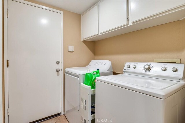 laundry room featuring cabinet space, light tile patterned floors, and washer and dryer