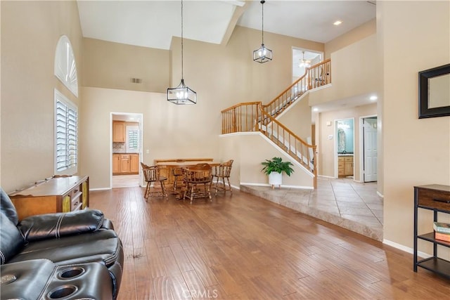 dining space featuring stairs, high vaulted ceiling, baseboards, and wood-type flooring