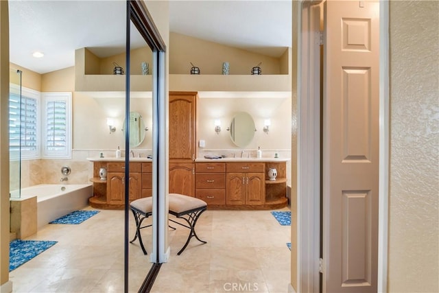 full bath with a bath, tile patterned floors, two vanities, and lofted ceiling
