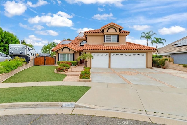 mediterranean / spanish house with a front yard, stucco siding, roof mounted solar panels, driveway, and a tile roof