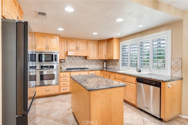 kitchen with a sink, appliances with stainless steel finishes, light brown cabinetry, and visible vents