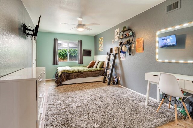 bedroom featuring baseboards, a textured wall, a ceiling fan, and visible vents