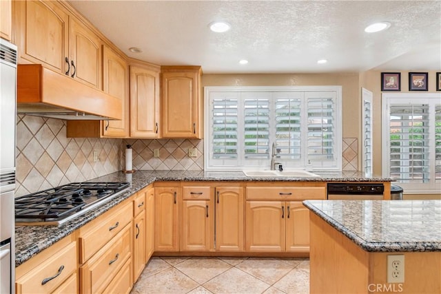 kitchen with light tile patterned flooring, a sink, stainless steel gas cooktop, dark stone countertops, and under cabinet range hood