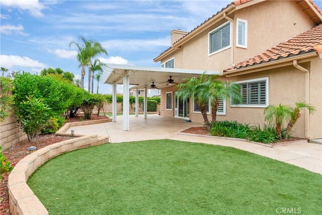 rear view of house with a lawn, a fenced backyard, ceiling fan, and a tiled roof