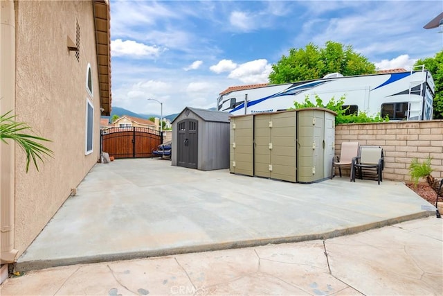 view of patio / terrace featuring an outdoor structure, a gate, a shed, and fence