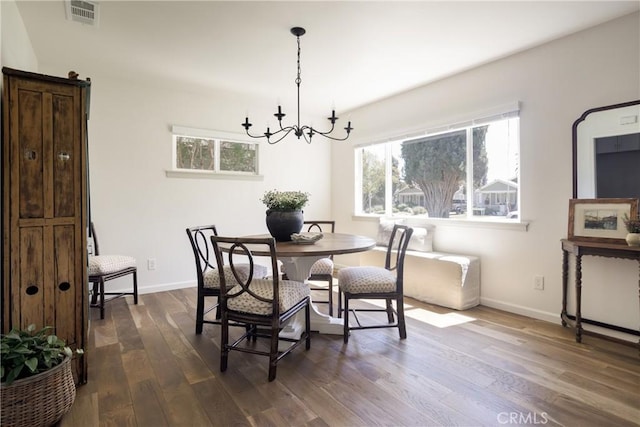 dining space featuring dark wood-style flooring, a notable chandelier, visible vents, and plenty of natural light