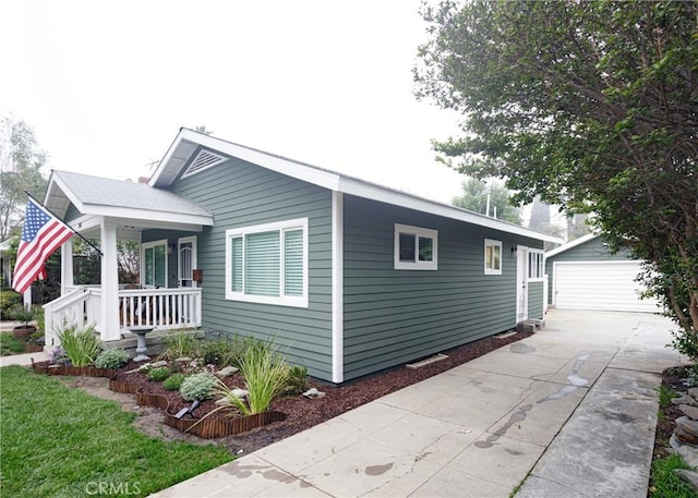 view of side of home featuring a garage, an outbuilding, and covered porch