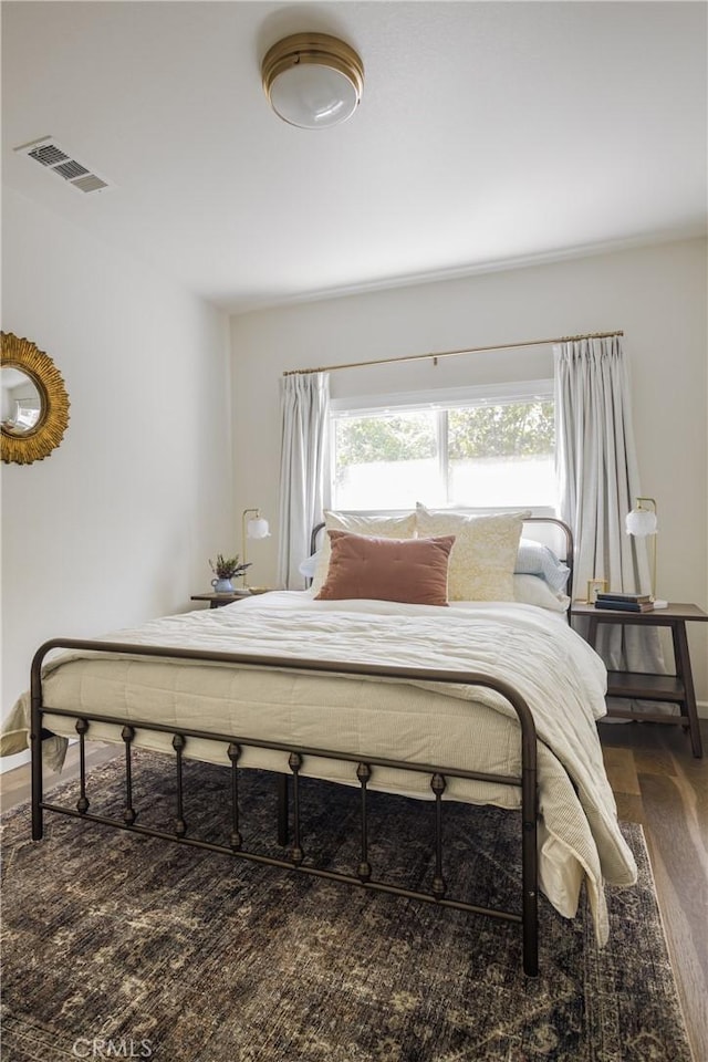 bedroom featuring baseboards, visible vents, and wood finished floors
