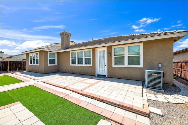 back of house with a patio, central air condition unit, a fenced backyard, a chimney, and stucco siding