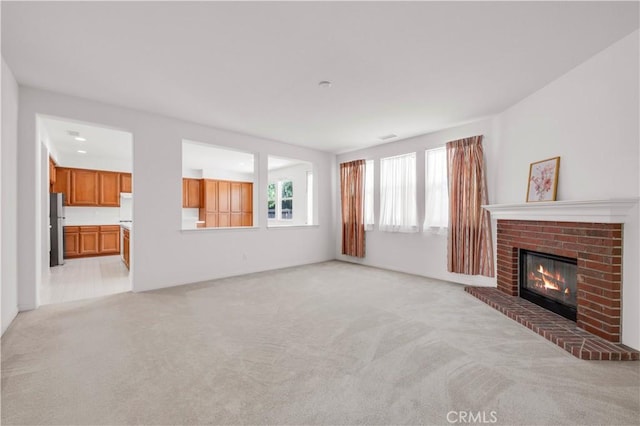 unfurnished living room featuring light colored carpet and a fireplace