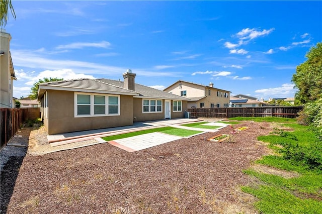 back of property with stucco siding, a chimney, a patio area, and a fenced backyard