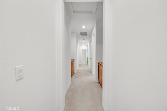 hall with baseboards, visible vents, attic access, and light colored carpet
