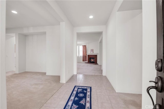foyer with light tile patterned flooring, baseboards, light colored carpet, and a fireplace