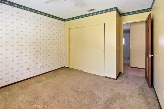 5655 Via Mensabe, Riverside, CA 92506 - unfurnished bedroom featuring carpet floors, a textured ceiling, a closet, wallpapered walls, and a ceiling fan