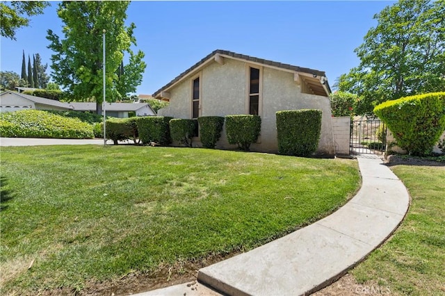 5655 Via Mensabe, Riverside, CA 92506 - view of property exterior featuring stucco siding, a gate, and a yard