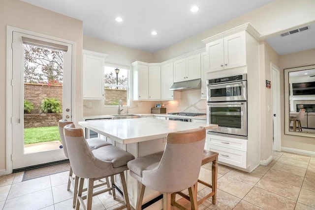 1693 Thompson Ave, Chula Vista, CA 91913 - kitchen with appliances with stainless steel finishes, under cabinet range hood, light countertops, a kitchen island, and white cabinets