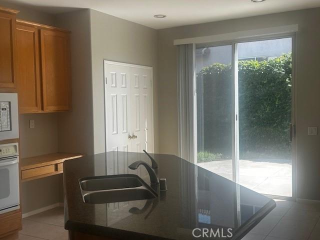 31329 Seminole St, Temecula, CA 92591 - kitchen with white appliances, light tile patterned floors, brown cabinets, and dark countertops