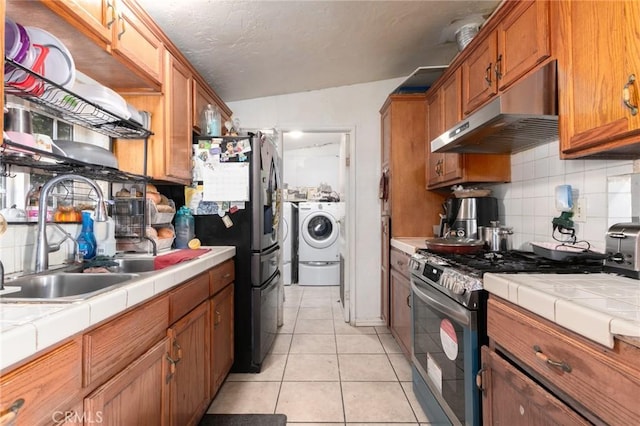 323 Whipple Mountain Rd, San Bernardino, CA 92410 - kitchen with tile countertops, appliances with stainless steel finishes, tasteful backsplash, washing machine and dryer, and under cabinet range hood