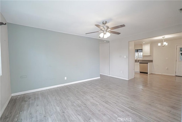 unfurnished living room featuring visible vents, baseboards, a sink, light wood finished floors, and ceiling fan with notable chandelier