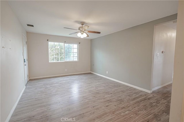 spare room with baseboards, ceiling fan, wood finished floors, and visible vents