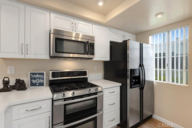 kitchen with appliances with stainless steel finishes, light countertops, baseboards, recessed lighting, and white cabinetry