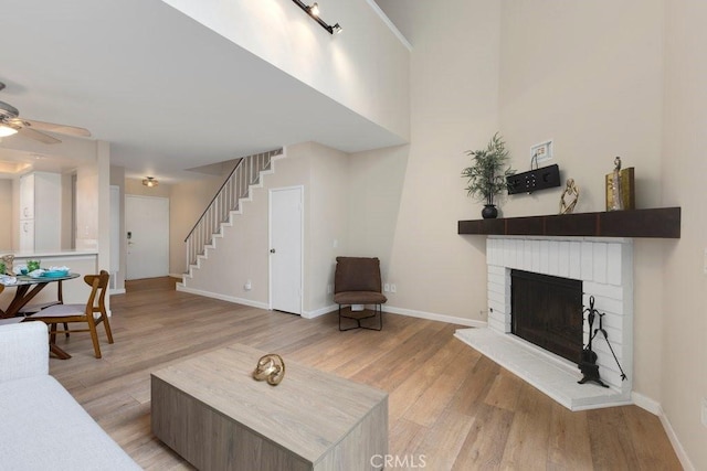 living area with stairway, ceiling fan, and light wood-style floors