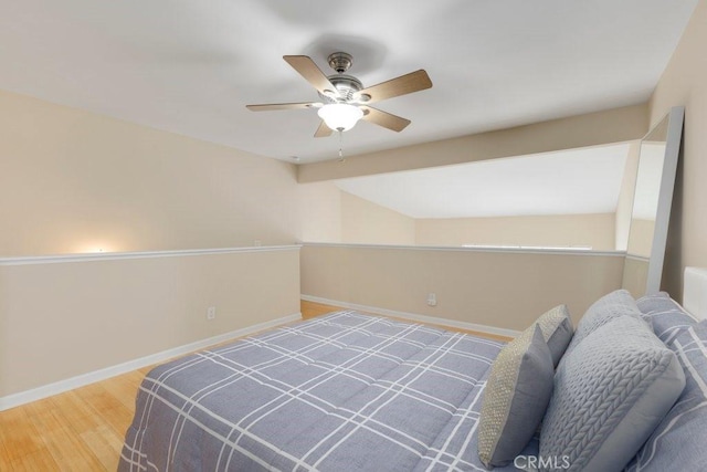bedroom with ceiling fan, baseboards, vaulted ceiling with beams, and wood finished floors