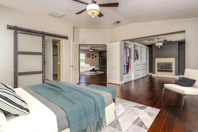 31746 Palomar Rd, Menifee, CA 92584 - bedroom with a barn door, hardwood / wood-style flooring, a tiled fireplace, lofted ceiling, and a closet