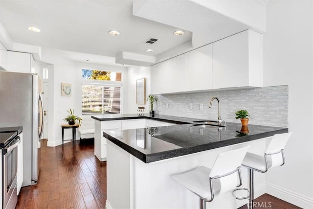 kitchen with decorative backsplash, a sink, visible vents, stainless steel electric range, and a peninsula
