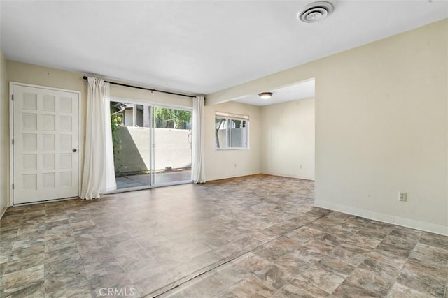 spare room featuring stone finish flooring, baseboards, and visible vents