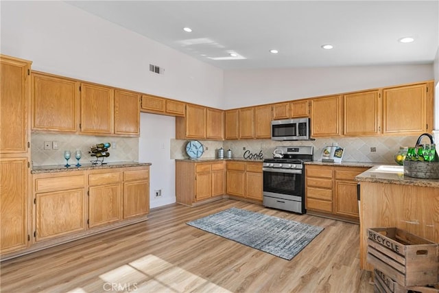 43 La Sordina, Rancho Santa Margarita, CA 92688 - kitchen with stainless steel appliances, light stone countertops, backsplash, high vaulted ceiling, and light wood-style floors