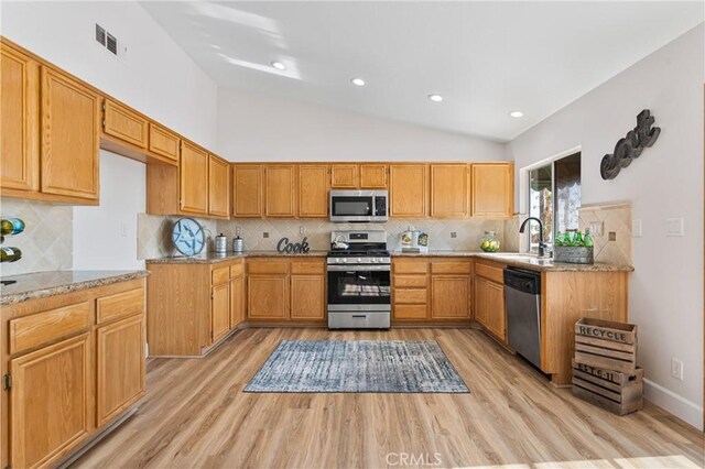 43 La Sordina, Rancho Santa Margarita, CA 92688 - kitchen with stainless steel appliances, light wood-style flooring, a sink, lofted ceiling, and backsplash