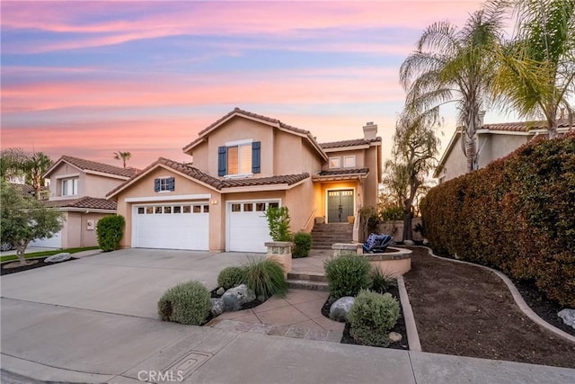 43 La Sordina, Rancho Santa Margarita, CA 92688 - view of front facade featuring driveway, stucco siding, a chimney, a tiled roof, and an attached garage