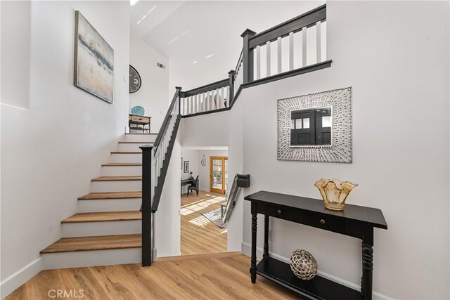 43 La Sordina, Rancho Santa Margarita, CA 92688 - staircase featuring baseboards, a towering ceiling, and wood finished floors