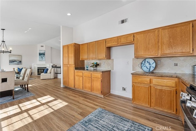 43 La Sordina, Rancho Santa Margarita, CA 92688 - kitchen featuring stainless steel range with gas stovetop, lofted ceiling, light wood finished floors, a chandelier, and tasteful backsplash