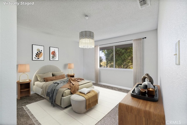 carpeted bedroom with visible vents, a textured ceiling, and a chandelier
