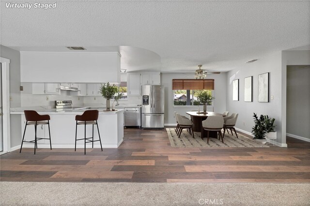 kitchen featuring ceiling fan, appliances with stainless steel finishes, light countertops, a peninsula, and visible vents