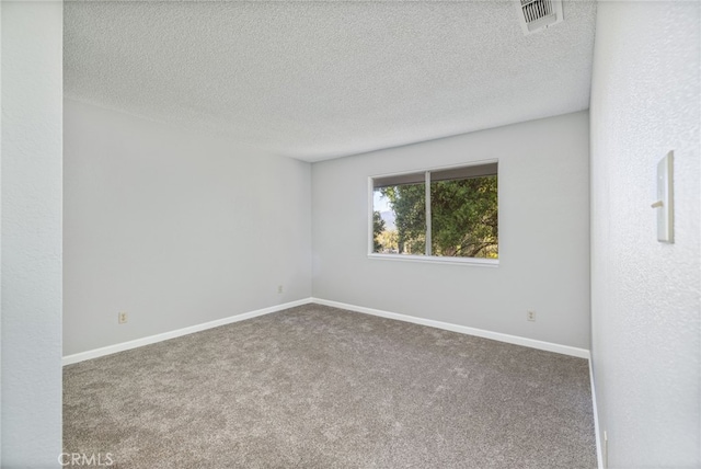 carpeted spare room featuring baseboards, a textured ceiling, and visible vents
